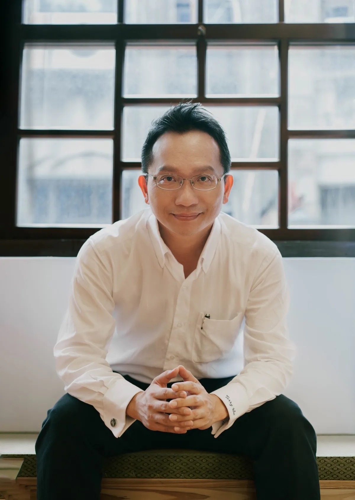 吳家德坐在老窗前雙手交握